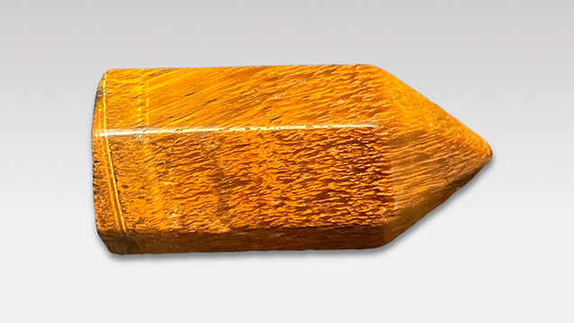 Figure 7. This polished specimen of tiger’s-eye (3.5 × 1.6 mm, 14.57 g) exhibits a golden yellow coloration similar to that of petrified tree fern. Photo by Ying Yan.