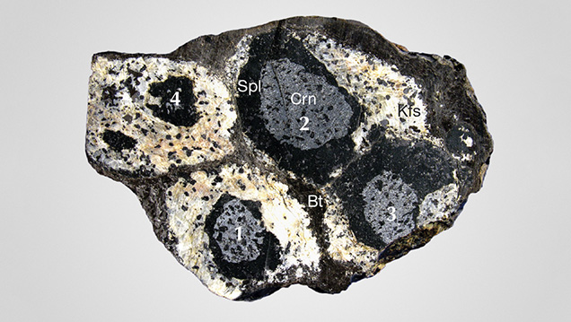 Stages of spinel corona formation around corundum grains