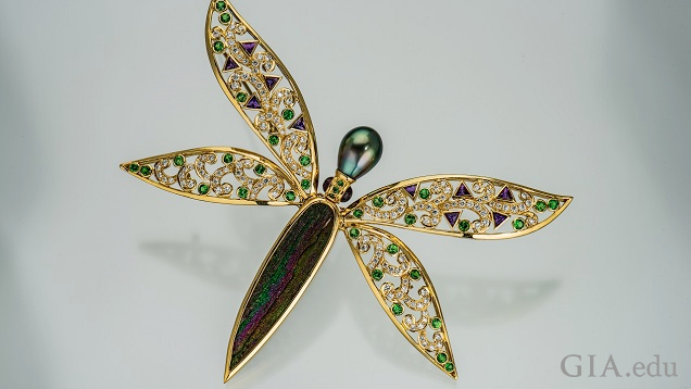 晶洞でできた体と真珠でできた頭部を持つトンボのピン。羽根には透明および緑色の宝石がセットされている。