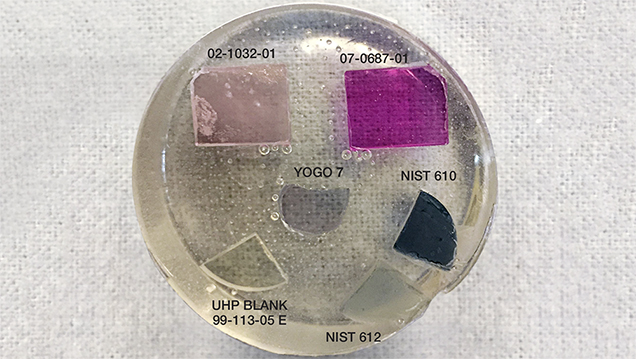 Figure 1. One of GIA’s new LA-ICP-MS corundum calibration standards sets (set number 1); the epoxy disk containing the set is 1.5 inches in diameter. NIST SRM 610 and 612 glass standards are included to account for trace and non-trace elements, such as those found in inclusions, that were not incorporated into the synthetic sapphire crystals grown for standards. Photo by Jennifer Stone-Sundberg.