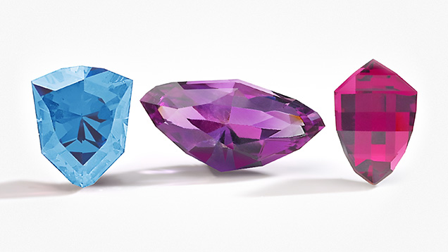 Figure 2. Gemstone cutters in Kenya, Malawi, and Zambia developed cuts to represent their countries in Virtu Gem’s National Gem Cut Course. Left to right: the Kenya Cheetah Head, Zambia Eagle, and Malawi <em>Mbuna</em> Fish cuts in aquamarine, amethyst, and rhodolite garnet. Photo courtesy of Virtu Gem.