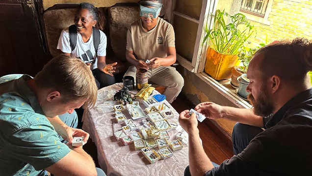Four people sitting around a table examining gems.