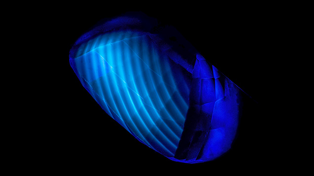 Figure 11. The curved banding in this flame-fusion synthetic blue sapphire is revealed by deep-UV illumination. From Hughes (2019); field of view ~13 mm.