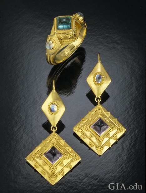 Triangle-shaped pieces with a tourmaline center drop from a diamond-shaped top with a moonstone center.