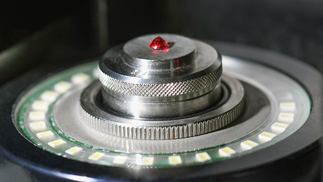 Figure 1. A red gemstone set table-down in a noncontact optical measurement device. Photo by Annie Haynes.