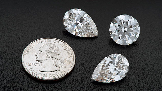 Figure 1. Three large CVD-grown diamonds submitted by Plasmability to GIA for scientific examination: A matching pair of pear-cut gems weighing 8.88 and 8.89 ct, as well as a 10.13 ct round brilliant. These American-grown diamonds are displayed with a U.S. quarter (24.26 mm diameter) for scale. Photo by Jian Xin (Jae) Liao. Figure 1. Three large CVD-grown diamonds submitted by Plasmability to GIA for scientific examination: A matching pair of pear-cut gems weighing 8.88 and 8.89 ct, as well as a 10.13 ct round brilliant. These American-grown diamonds are displayed with a U.S. quarter (24.26 mm diameter) for scale. Photo by Jian Xin (Jae) Liao.