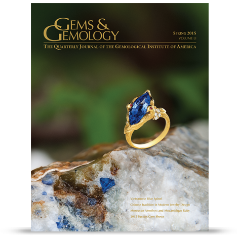 A gold ring with a blue gemstone is featured on the cover of a gemology journal, set against a natural stone background.