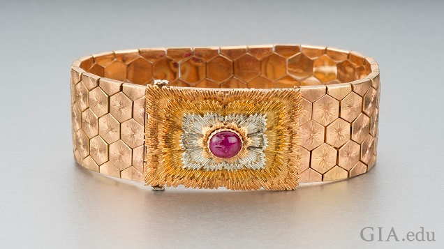 Wide rose gold patterned bracelet features a ruby cabochon.
