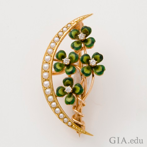 Four clover leaves climb up a branch – framed on the left side with a crescent of pearls.