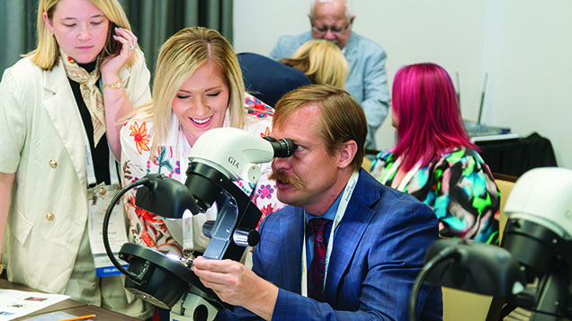 Figure 3. Aaron Palke helps orient a treated gemstone under the microscope for seminar attendees to view its diagnostic inclusions. Photo by Emily Lane.
