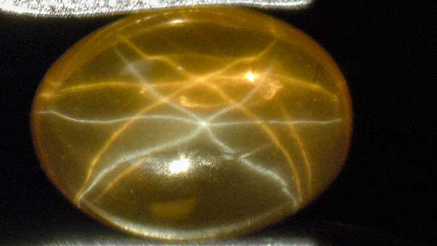Yellow-orange synthetic sapphire with a white star and a yellow-orange star