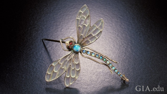 View of a dragonfly brooch from above. Translucent wings and body of blueish opal.