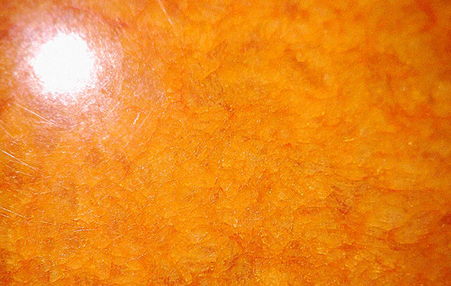 Figure 2. The 140.58 ct sphere exhibited a mosaic structure, and orange color concentration was noted within areas under magnification. Photomicrograph by Cheryl (Ying Wai) Au; field of view 6.92 mm.