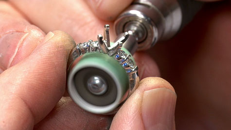 Close-up view of a jeweler using a rotary burnisher to prefinish the inside of a platinum ring