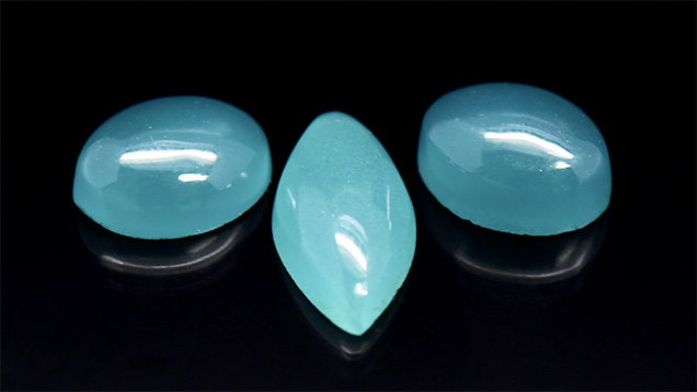 Three greenish blue glass cabochon samples.