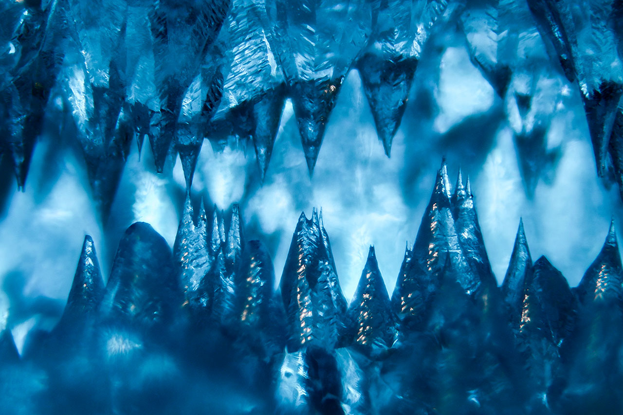 This aquamarine has been significantly etched, resulting in a cave-like cavity filled with sharp spires of beryl. Field of view 3.28 mm.