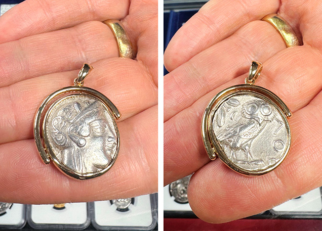 A hand holds a pendant featuring a coin with a detailed face on one side and an owl on the other, framed in gold.