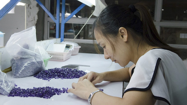Chinese woman examines rough gemstones