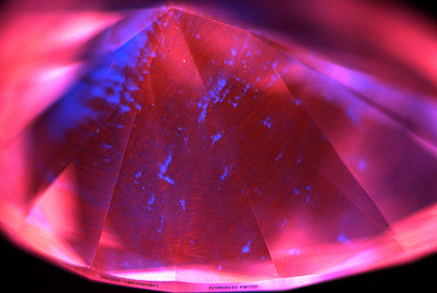 Figure 2. Representative deep-UV fluorescence image of a 2.90 ct CVD diamond from Plasmability, collected using the DiamondView. The image is dominated by red–orange fluorescence from NV<sup>0</sup> centers, a common feature for untreated CVD laboratory-grown diamonds, along with irregular blue fluorescing dislocation bundles. No growth layers were observed, indicating that it was produced through a single uninterrupted growth cycle. Image by Madelyn Dragone. Figure 2. Representative deep-UV fluorescence image of a 2.90 ct CVD diamond from Plasmability, collected using the DiamondView. The image is dominated by red–orange fluorescence from NV<sup>0</sup> centers, a common feature for untreated CVD laboratory-grown diamonds, along with irregular blue fluorescing dislocation bundles. No growth layers were observed, indicating that it was produced through a single uninterrupted growth cycle. Image by Madelyn Dragone.