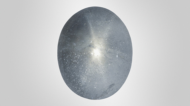 Figure 1. A 13.37 ct grayish blue aquamarine displaying asterism. Photo by Towfiq Ahmed.