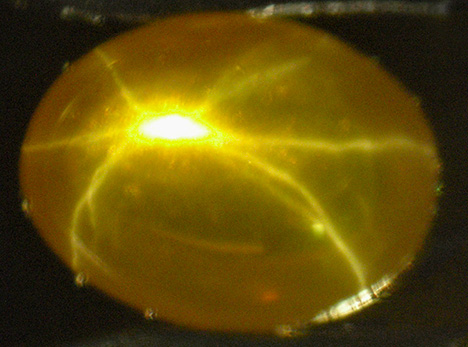 Yellow-orange synthetic sapphire showing star in transmitted light