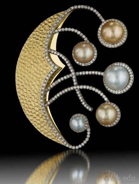 A crescent moon-shaped pin with “arms” that reach out from its center. Each “arm” holds a pearl at the end.