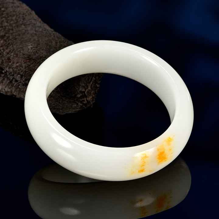 Figure 1. A high-quality Russian white nephrite bracelet, measuring approximately 58 × 13 × 7 mm, with the orange peel effect observable in its reflective areas. Photo by Zuojiang Chen.