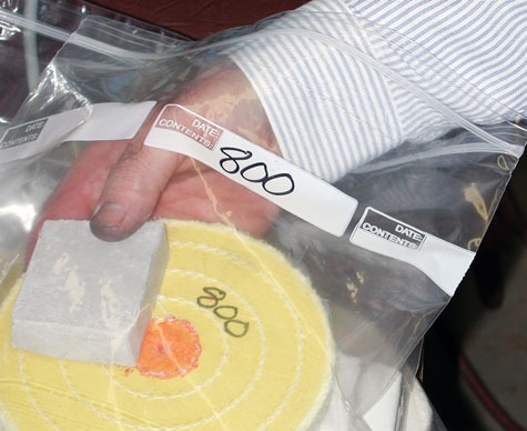 「800」と表示された黄色のプラチナ研磨用ホイールと研磨剤を、同様に「800」と表示された個別の保存バッグに入れるジュエラー。