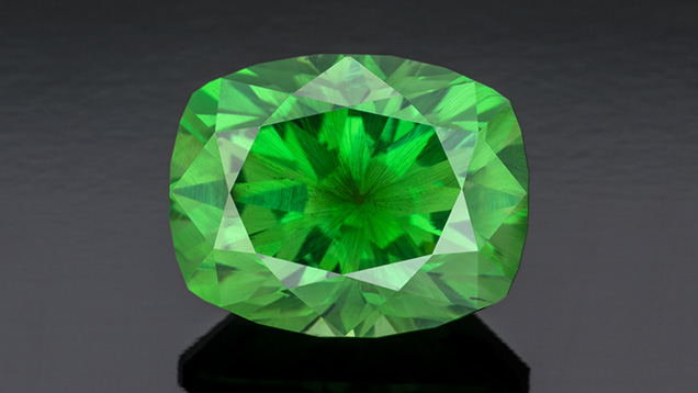 Figure 4. A 5.34 ct vivid green modified cushion-cut Russian demantoid garnet displaying horsetail inclusions. Photo by Robert Weldon; courtesy of Tsarina Jewels.