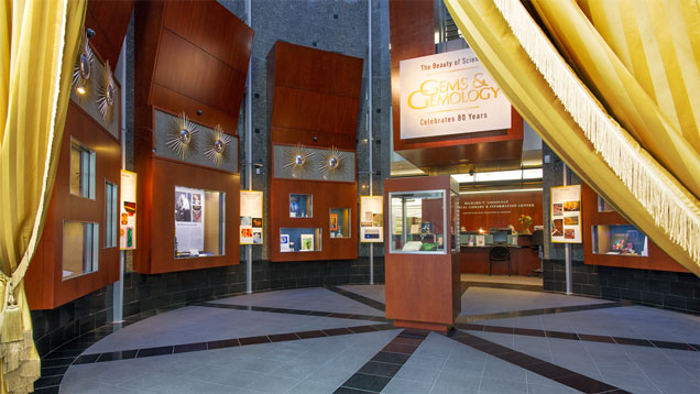 金色窗帘环绕 GIA 展览的入口，展览名为“科学之美：《宝石与宝石学》(Gems & Gemology) 庆祝创刊 80 周年，展示 Harold（哈罗德）和 Erica Van Pelt（艾丽卡·范·佩尔特）的艺术瑰宝”。摄影：Kevin Schumacher（凯文·舒马赫）/GIA，所有《宝石与宝石学》(Gems & Gemology) 照片均由 Harold（哈罗德）和 Erica Van Pelt（艾丽卡·范·佩尔特）提供