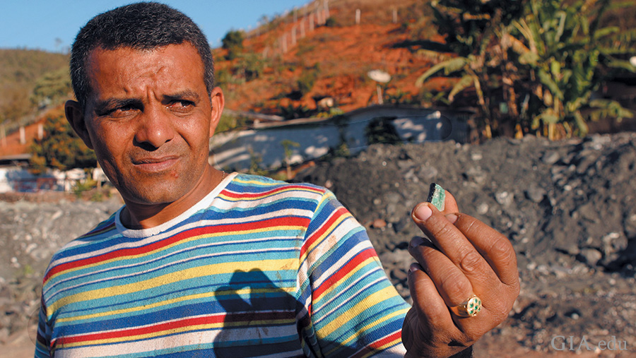 Miner holding a rough emerald at the Capoeirana mining area where the May birthstone is found. Miner holding a rough emerald at the Capoeirana mining area where the May birthstone is found.