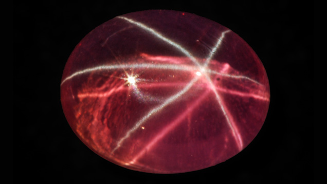 こちら白及びピンクの二つの六条の星（スター）彩効果をもつピンクの合成サファイアは、２０１０年にバンコクで著者の一人が購入しました。 カボションの寸法は14.4×11.2mmで、重量は12.37ctである。 写真提供：M.P. Steinbach.