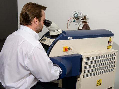 从业人员坐在激光焊机旁焊接一枚铂金戒指