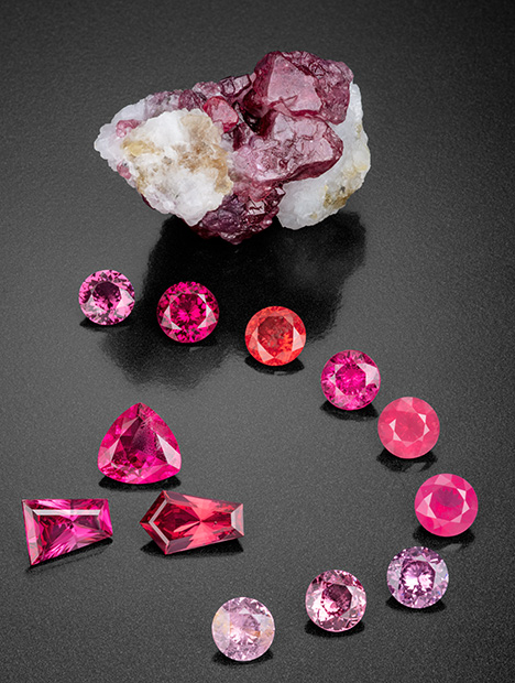 Figure 2. This remarkable suite of spinel gems faceted by Bill Vance shows a wonderful range of color and transparency. The 232.9 ct rough mineral specimen gives clues to the crystal’s origin, with remnants of the marble host rock preserved. The faceted