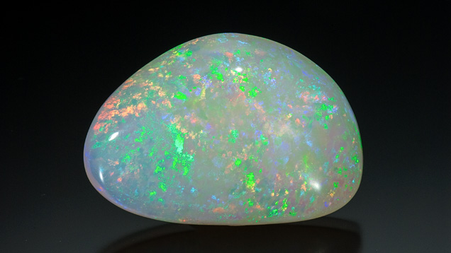 117.85 Carat Australian Light Opal Cabochon. This large Australian light opal cabochon weighs 117.85 carats. Small play-of-color flashes of orange and green predominate in a pinfire pattern, with spots of a more muted blue over a grayish bodycolor.