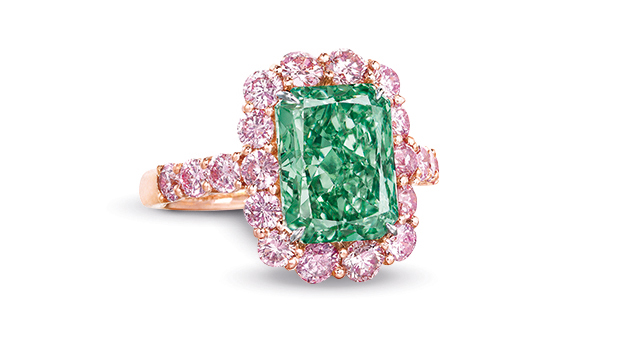 The Aurora Green Fancy Vivid green diamond is rectangle cut and mounted in a ring surrounded by Fancy pink melee diamonds.